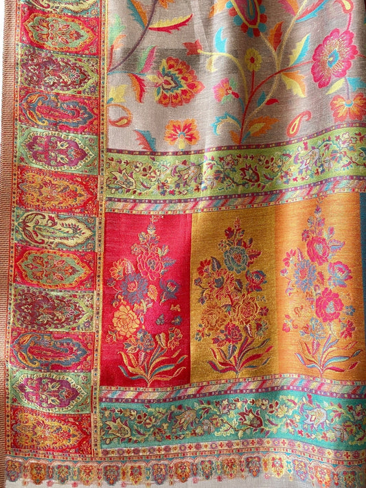 A multicolored Kani silk saree shawl with geometric and floral pattern, predominantly in red and gold, displayed on a hanger.